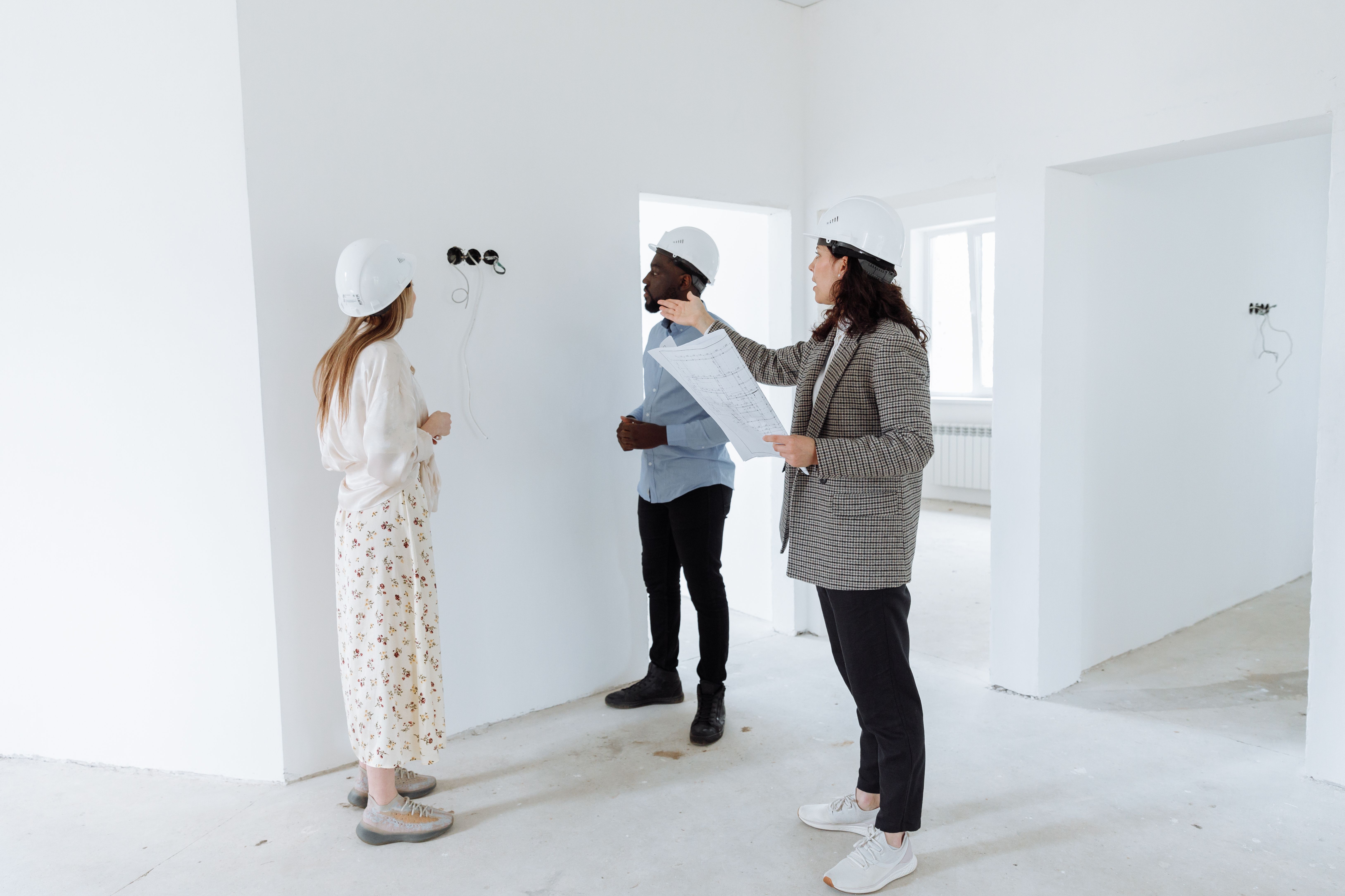 Professionals discussing design plans inside a new home, representing contractor consultations with prospective clients.